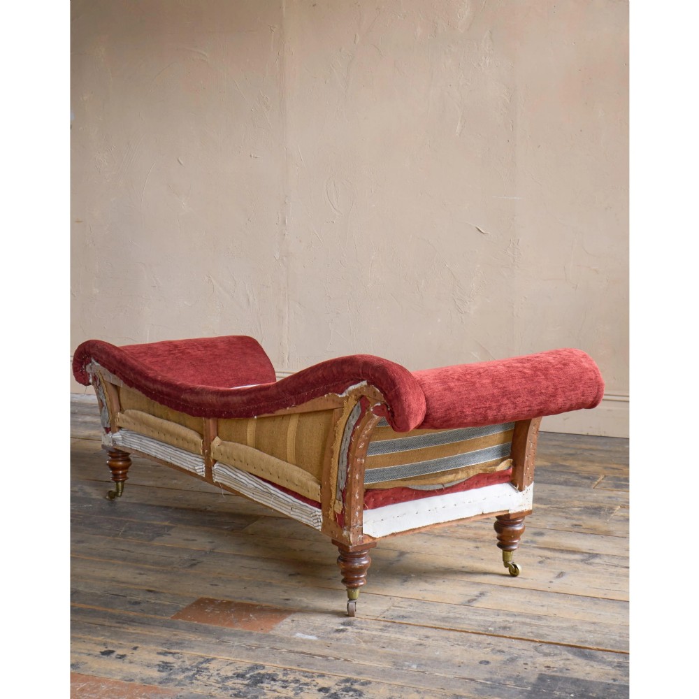 A Victorian asymmetrical chaise longue featuring red velvet and white calico fabric upholstery set on turned mahogany legs with brass castors. View IV