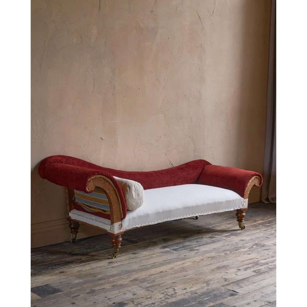 A Victorian asymmetrical chaise longue featuring red velvet and white calico fabric upholstery set on turned mahogany legs with brass castors. View V