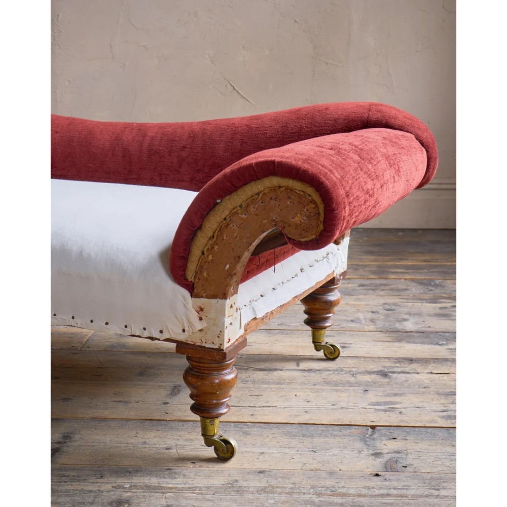 A Victorian asymmetrical chaise longue featuring red velvet and white calico fabric upholstery set on turned mahogany legs with brass castors. View VII