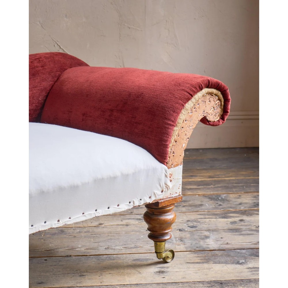 A Victorian asymmetrical chaise longue featuring red velvet and white calico fabric upholstery set on turned mahogany legs with brass castors. View VIII
