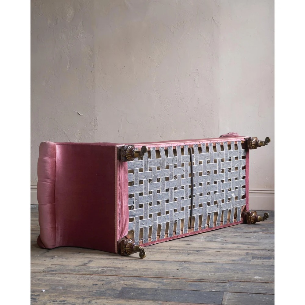 A Victorian deep-buttoned rose pink velvet chaise longue featuring carved mahogany Ionic column legs on brass castors with a loose white seat cushion. View IX