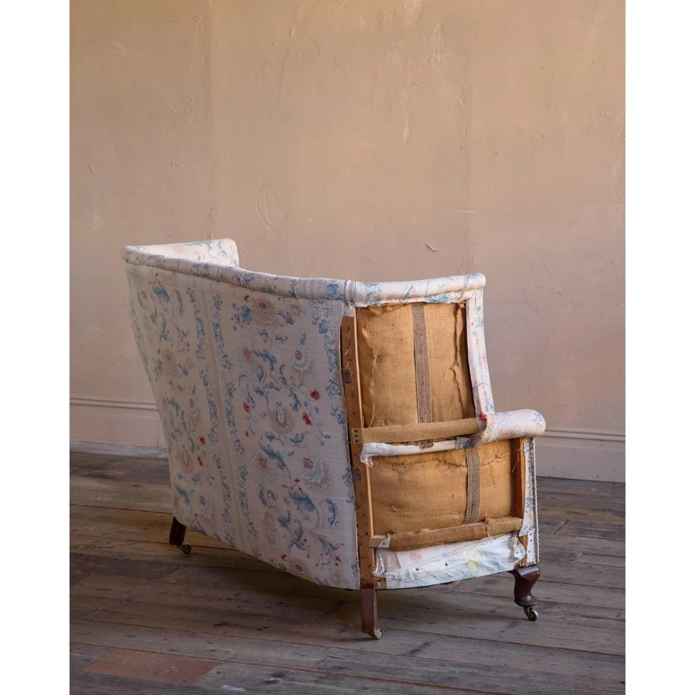 A nineteenth-century fluted wingback sofa featuring patterned floral upholstery, vertical channel tufting, and turned timber legs with brass castors. View V