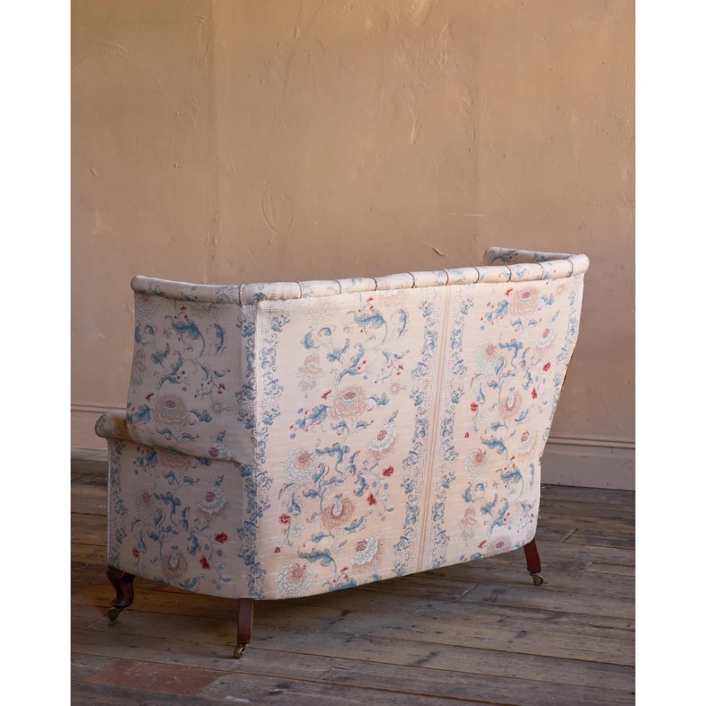 A nineteenth-century fluted wingback sofa featuring patterned floral upholstery, vertical channel tufting, and turned timber legs with brass castors. View VI