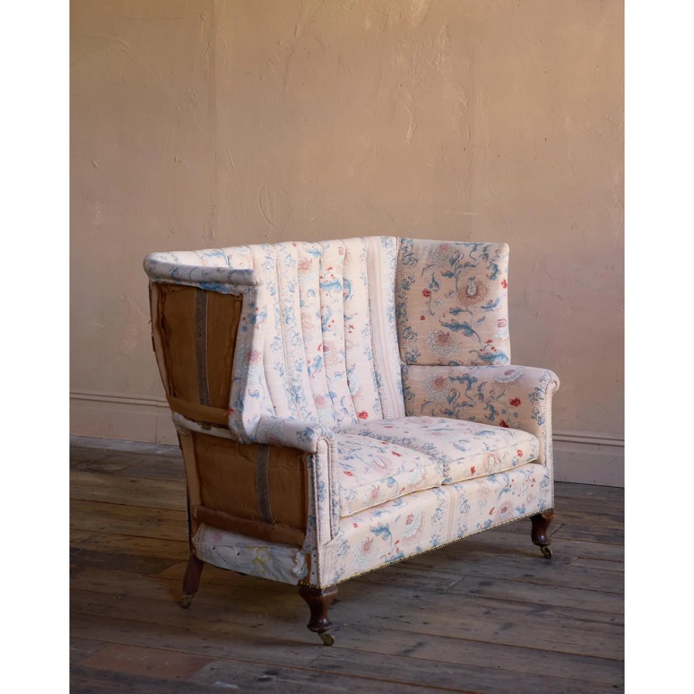 A nineteenth-century fluted wingback sofa featuring patterned floral upholstery, vertical channel tufting, and turned timber legs with brass castors. View VII