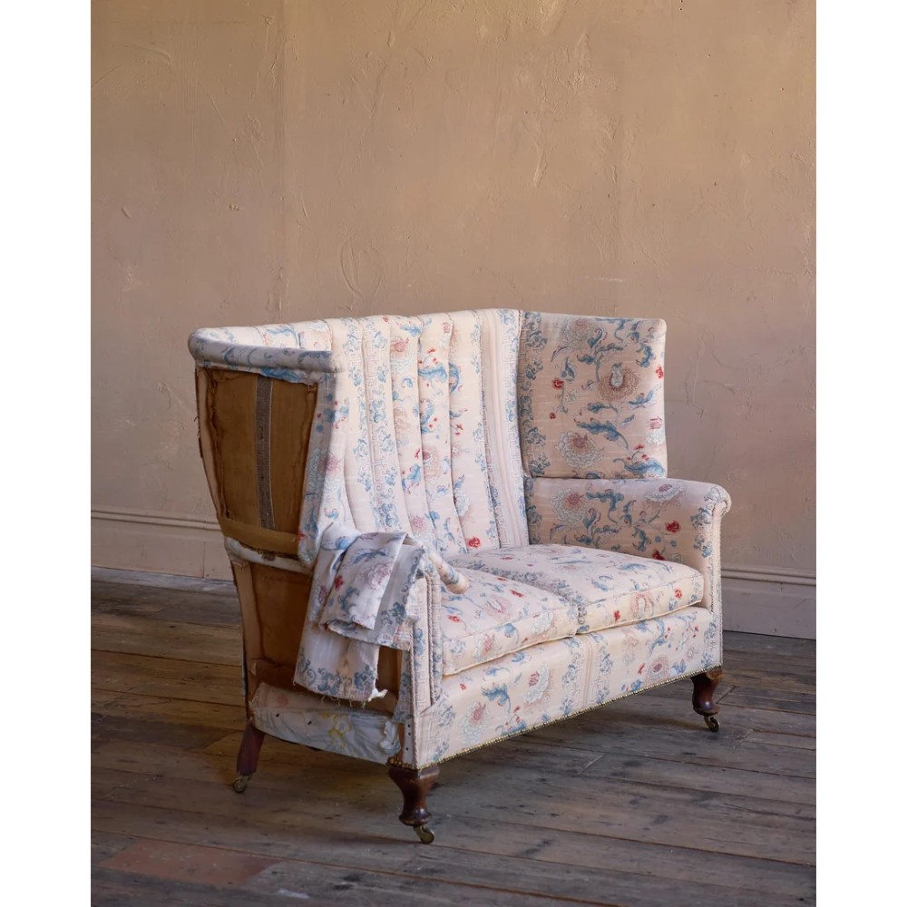 A nineteenth-century fluted wingback sofa featuring patterned floral upholstery, vertical channel tufting, and turned timber legs with brass castors. View VIII