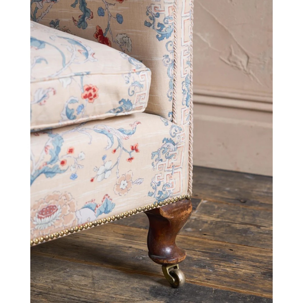 A nineteenth-century fluted wingback sofa featuring patterned floral upholstery, vertical channel tufting, and turned timber legs with brass castors. View X