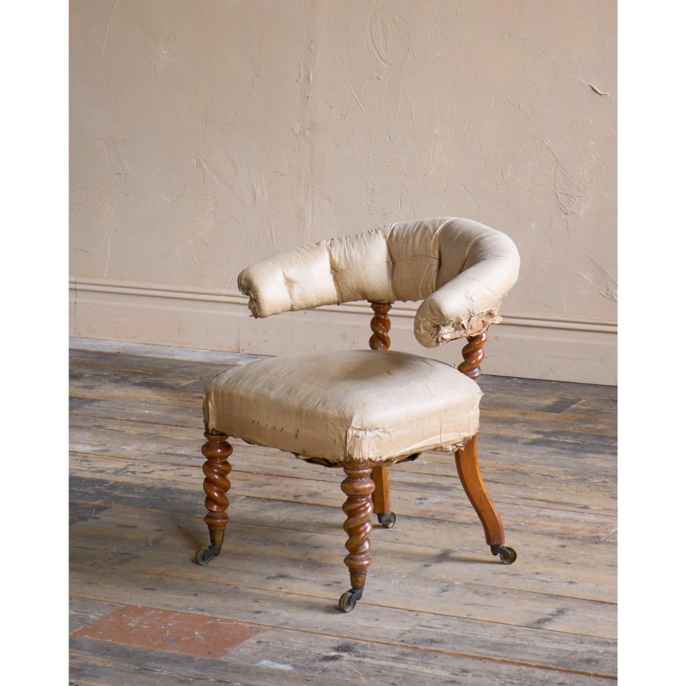 A Victorian low reading armchair with cream calico buttoned upholstery, spiral turned front legs, sabre rear legs, and brass castors. View II