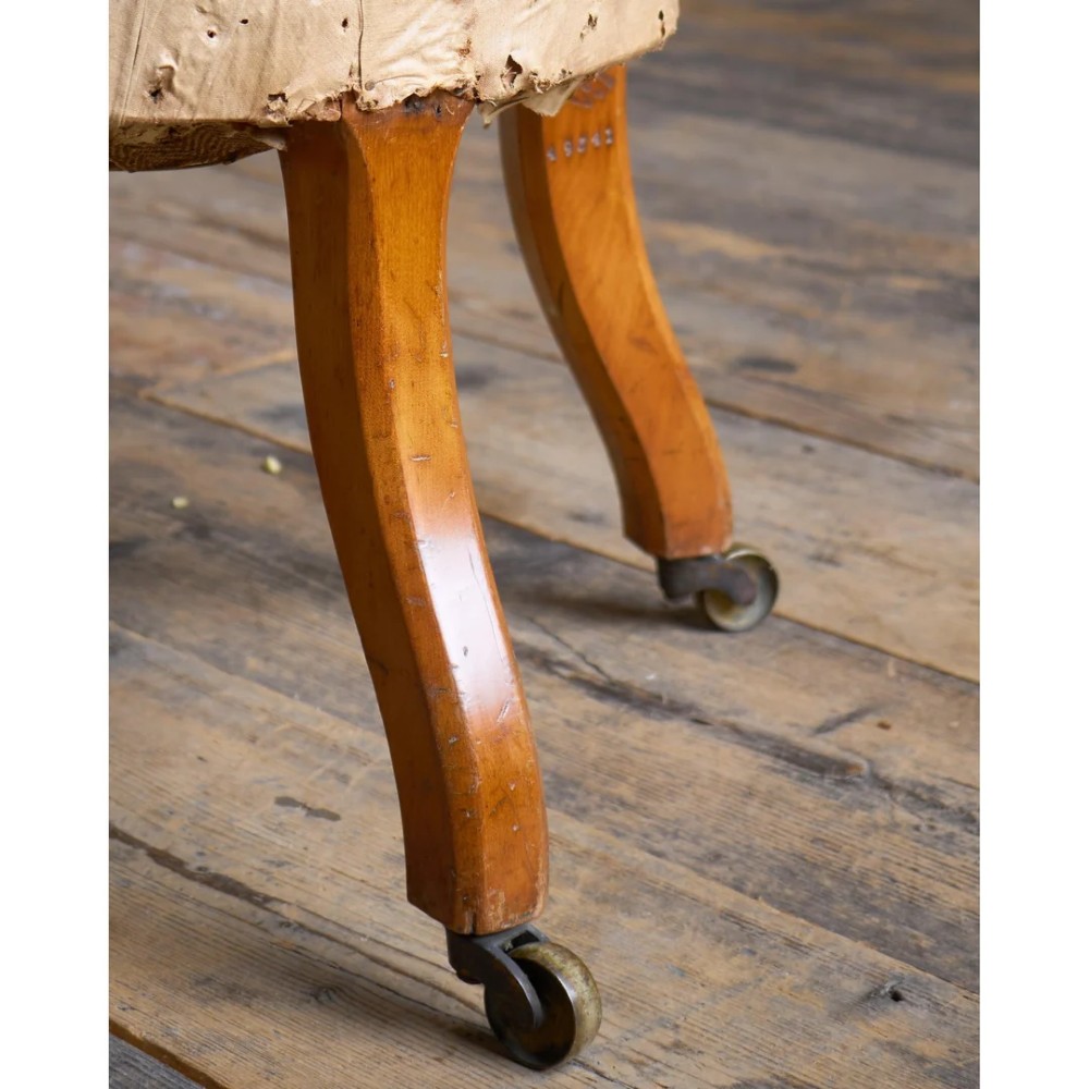 A Victorian low reading armchair with cream calico buttoned upholstery, spiral turned front legs, sabre rear legs, and brass castors. View IX