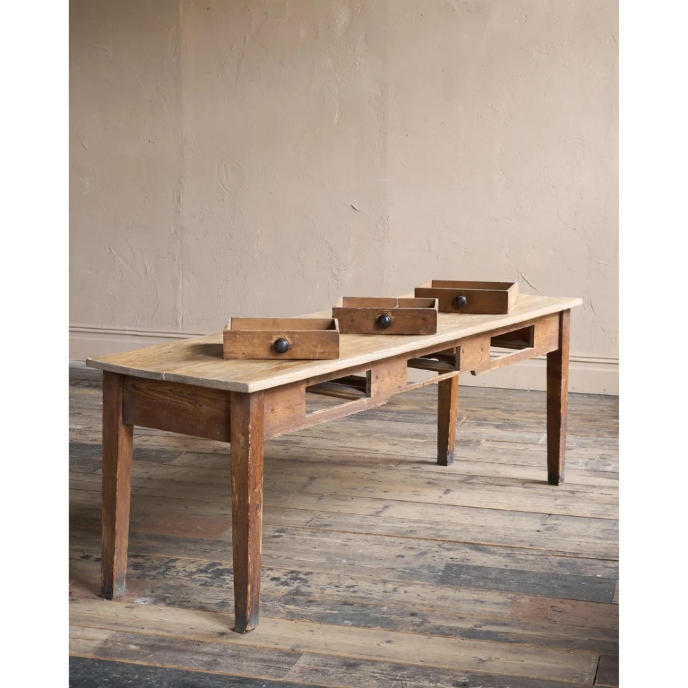 A long natural pine scullery table featuring three drawer fronts with dark wooden knobs and straight legs. View III