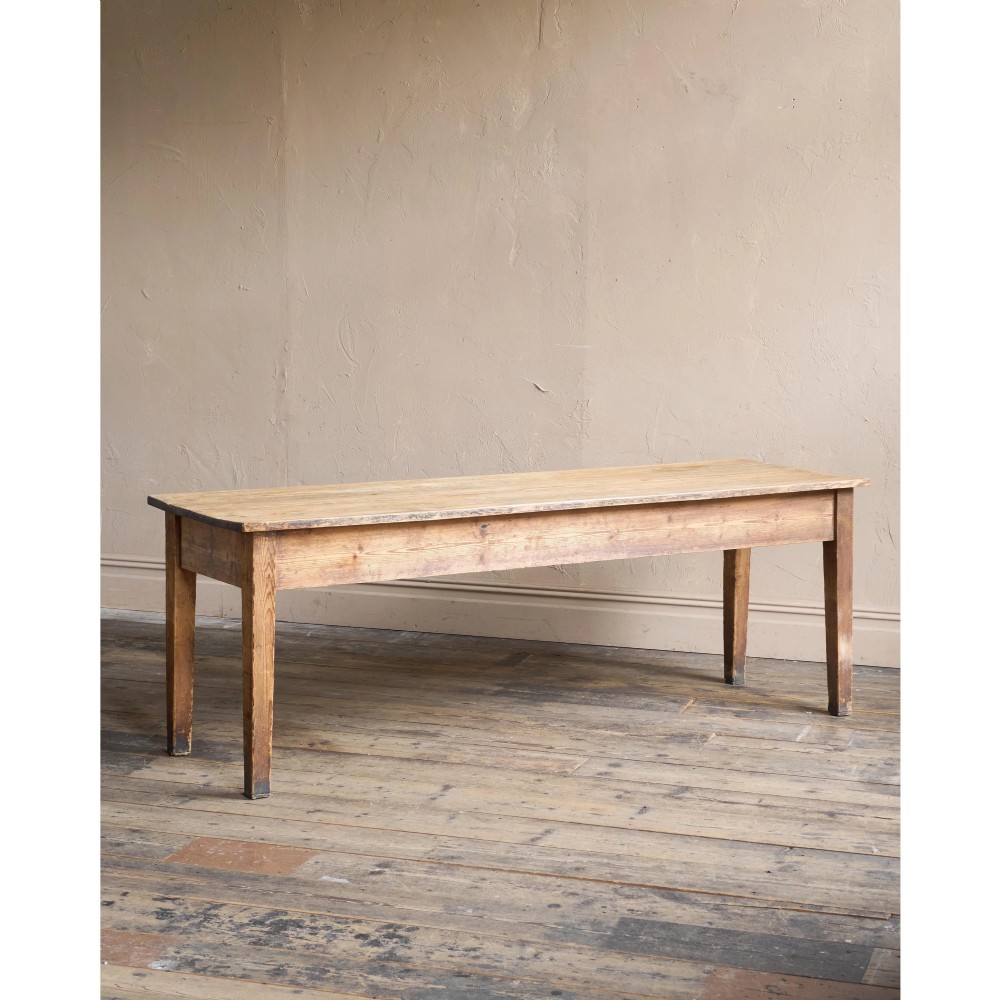 A long natural pine scullery table featuring three drawer fronts with dark wooden knobs and straight legs. View X