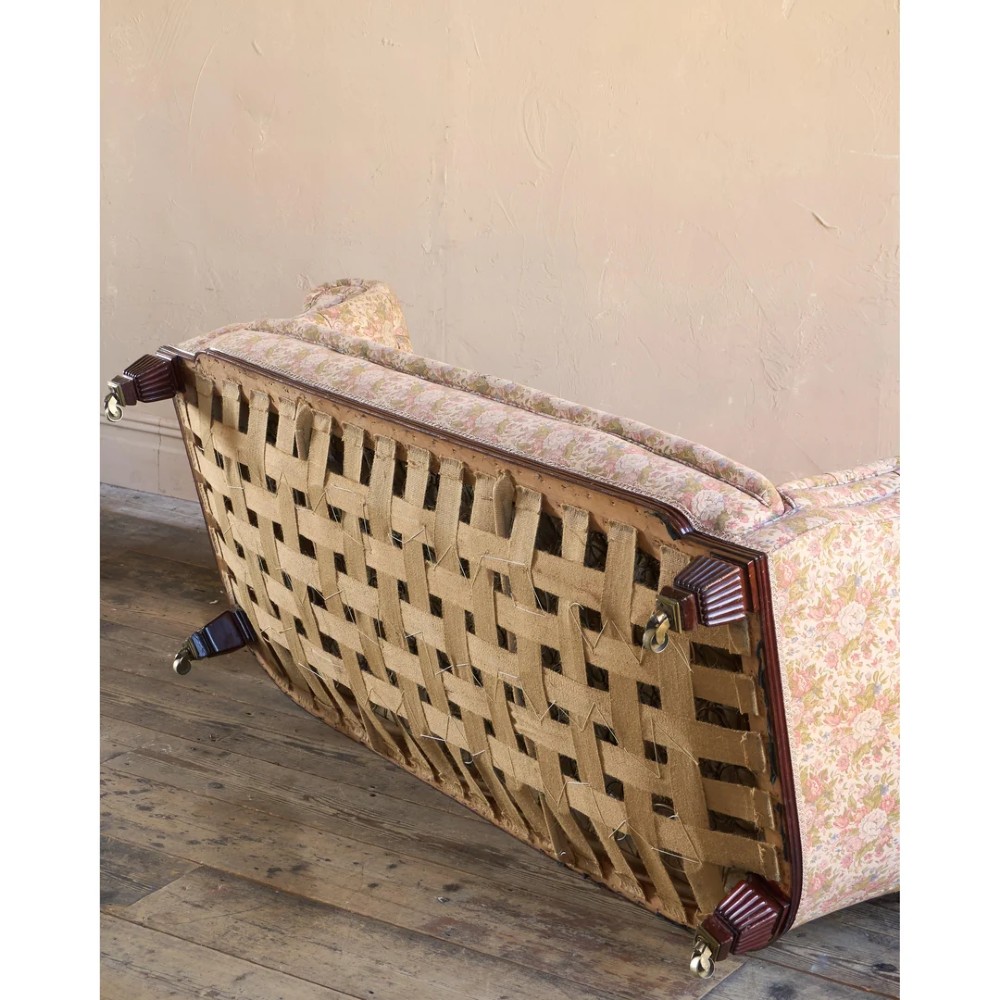 A nineteenth-century Chesterfield sofa with patterned floral upholstery, deep button tufting on the backrest and rolled arms, loose seat cushions, and turned legs on brass castors. View IX