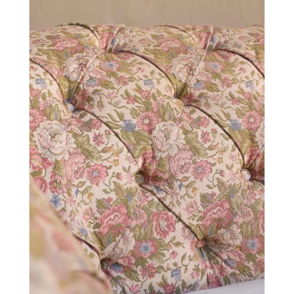 A nineteenth-century Chesterfield sofa with patterned floral upholstery, deep button tufting on the backrest and rolled arms, loose seat cushions, and turned legs on brass castors. View XIII