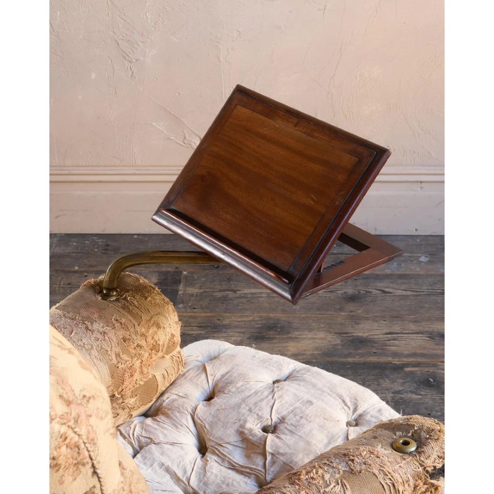 A 19th-century Victorian library armchair upholstered in beige floral pattern fabric with deep buttoning, turned front legs on castors, and an attached adjustable mahogany reading stand. View X