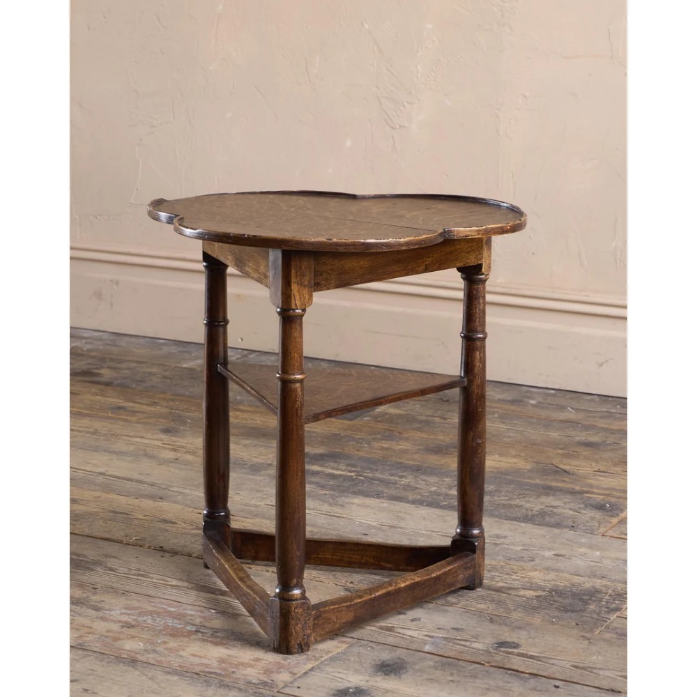 An 18th-century dark oak cricket table featuring a trefoil-shaped top, three turned legs, a triangular lower shelf, and a stretcher base. View IV