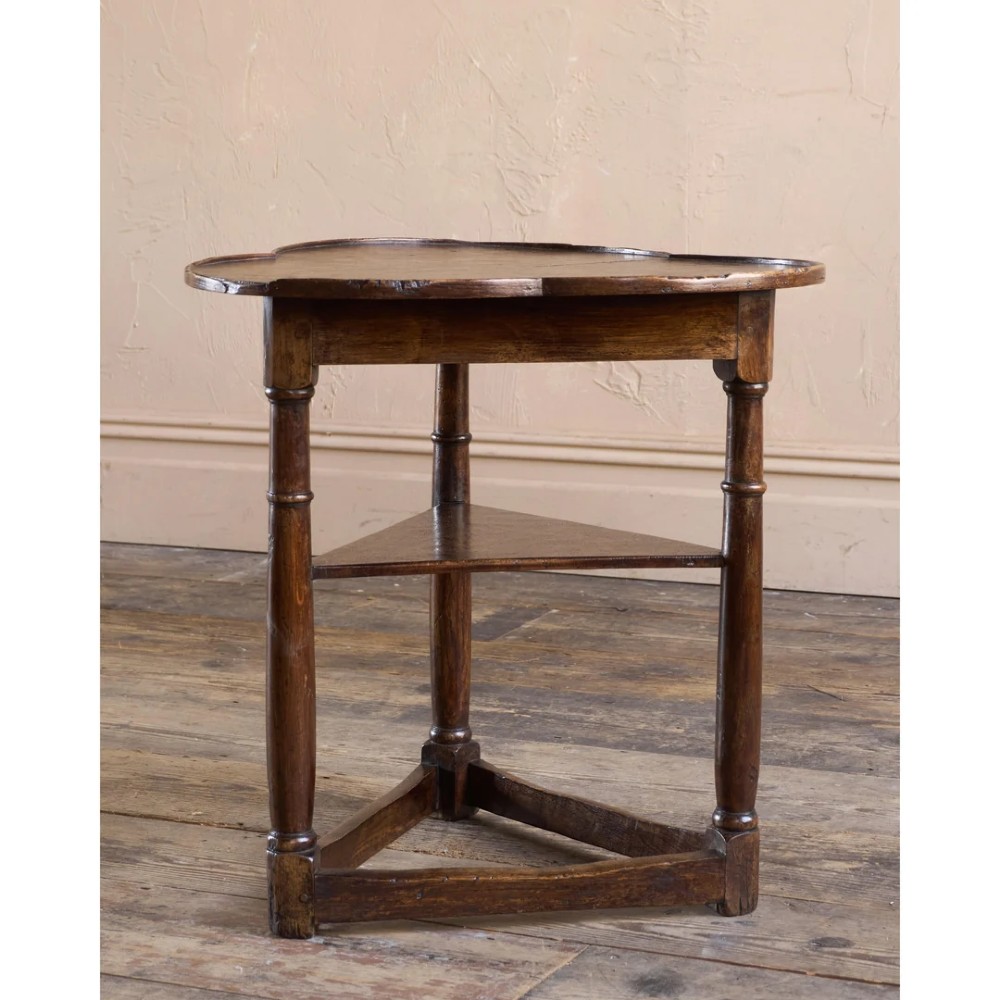 An 18th-century dark oak cricket table featuring a trefoil-shaped top, three turned legs, a triangular lower shelf, and a stretcher base. View VII