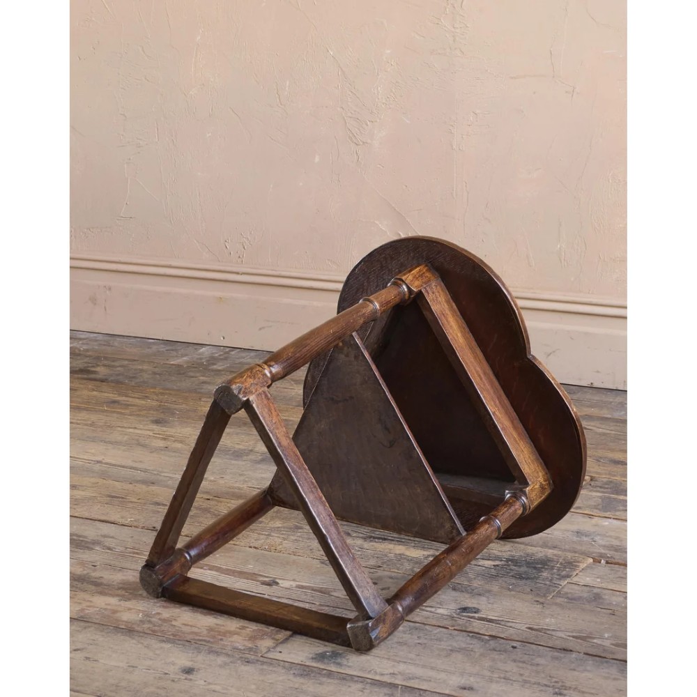An 18th-century dark oak cricket table featuring a trefoil-shaped top, three turned legs, a triangular lower shelf, and a stretcher base. View VIII