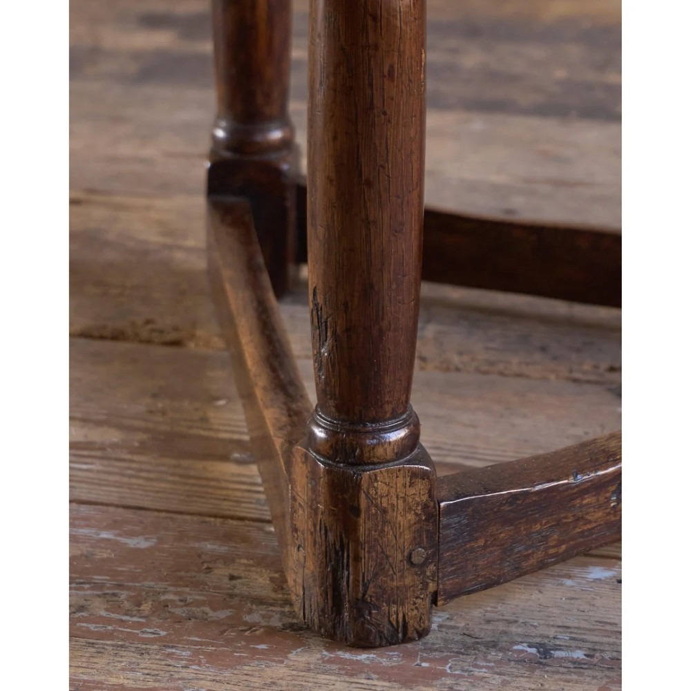An 18th-century dark oak cricket table featuring a trefoil-shaped top, three turned legs, a triangular lower shelf, and a stretcher base. View XV