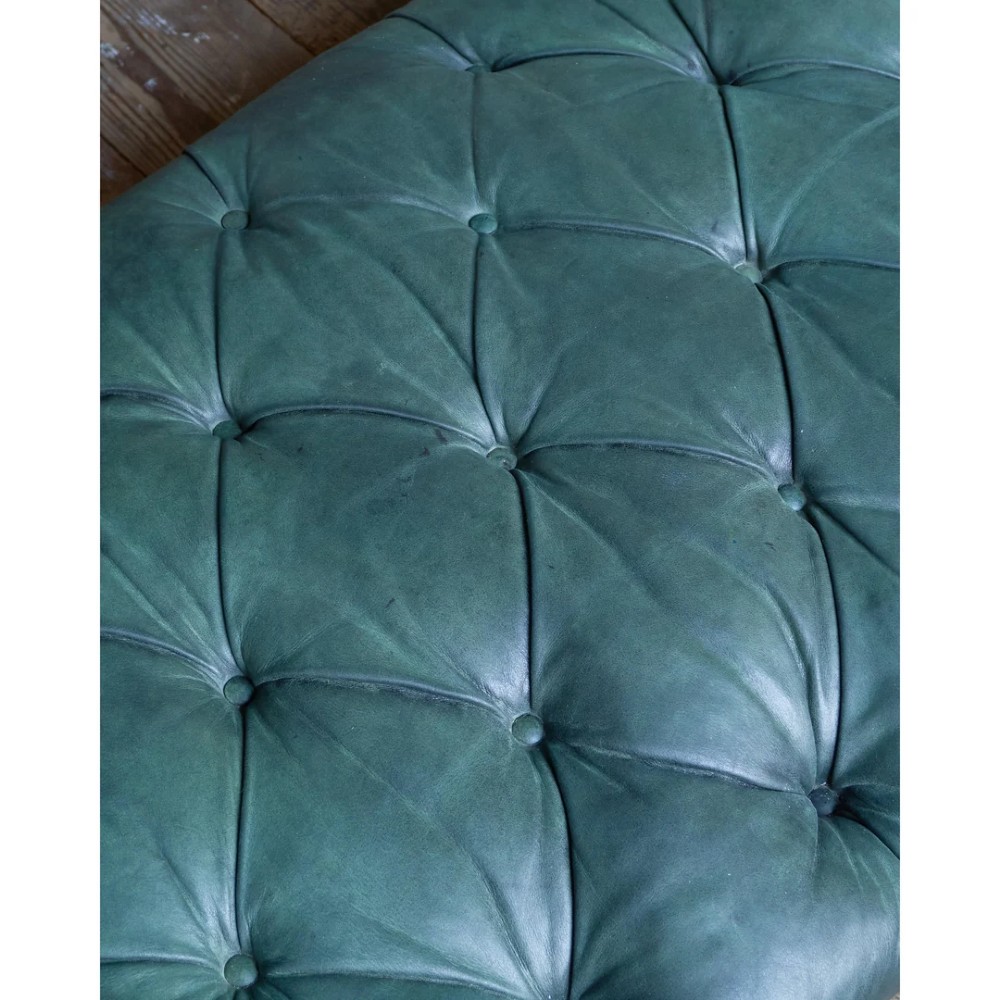 A deep buttoned green leather chaise longue featuring brass stud details, turned wood legs, and brass castors. View IX