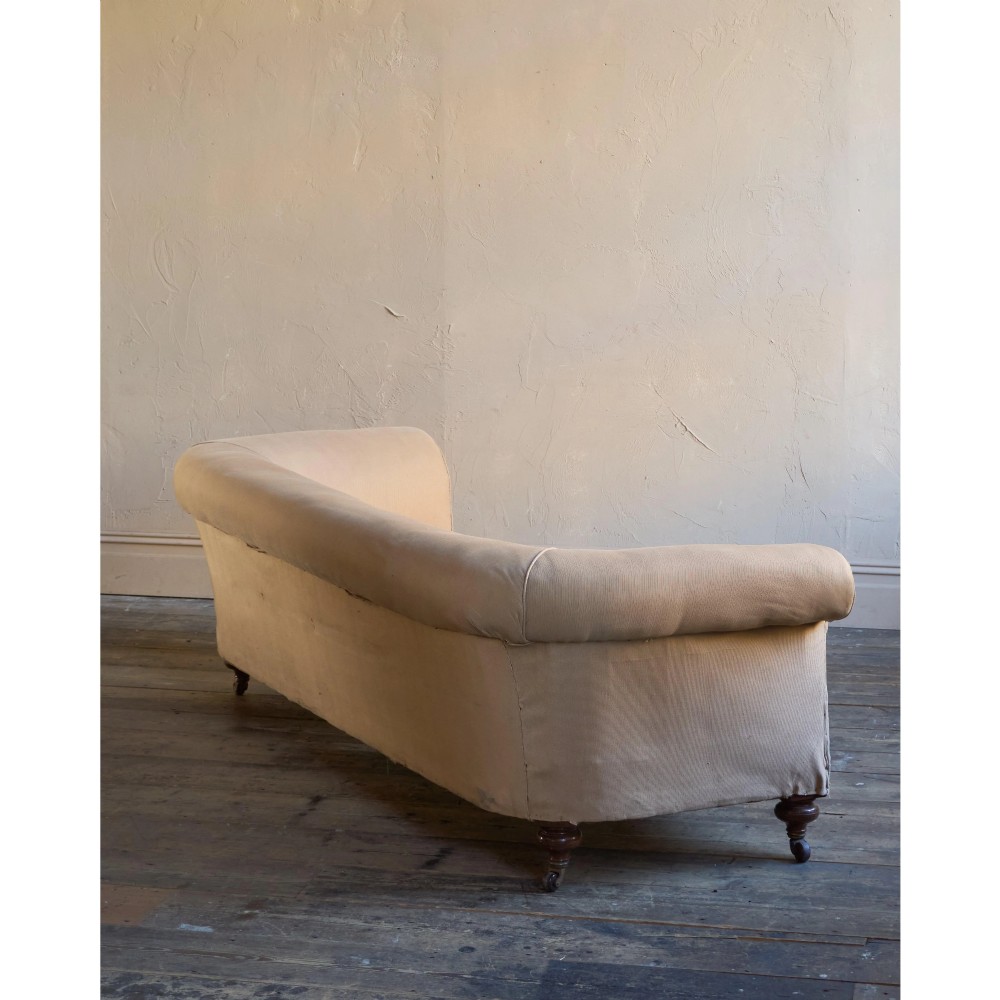 A 19th-century Chesterfield sofa upholstered in neutral beige calico fabric featuring rolled arms and turned wooden legs on brass castors. View V
