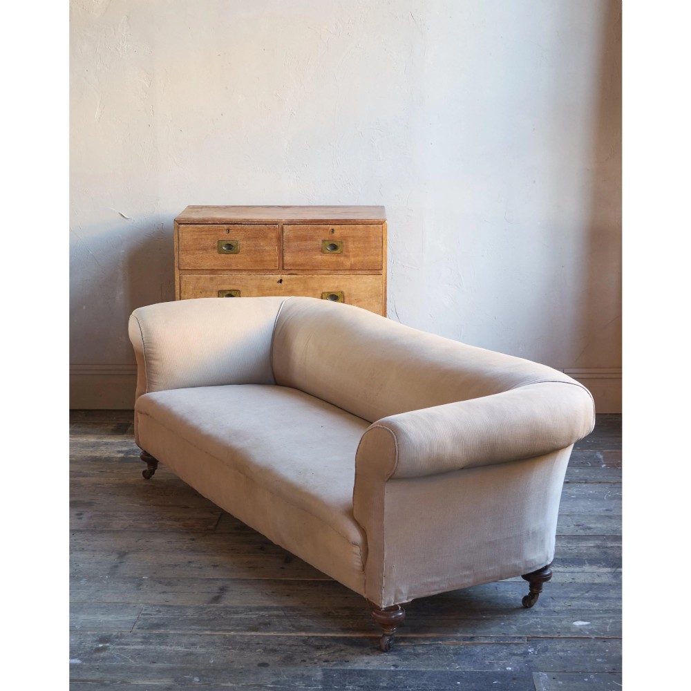 A 19th-century Chesterfield sofa upholstered in neutral beige calico fabric featuring rolled arms and turned wooden legs on brass castors. View VII