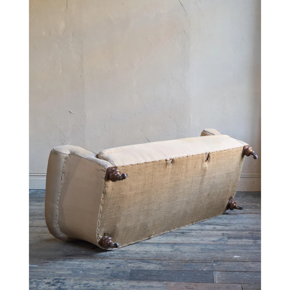 A 19th-century Chesterfield sofa upholstered in neutral beige calico fabric featuring rolled arms and turned wooden legs on brass castors. View VIII