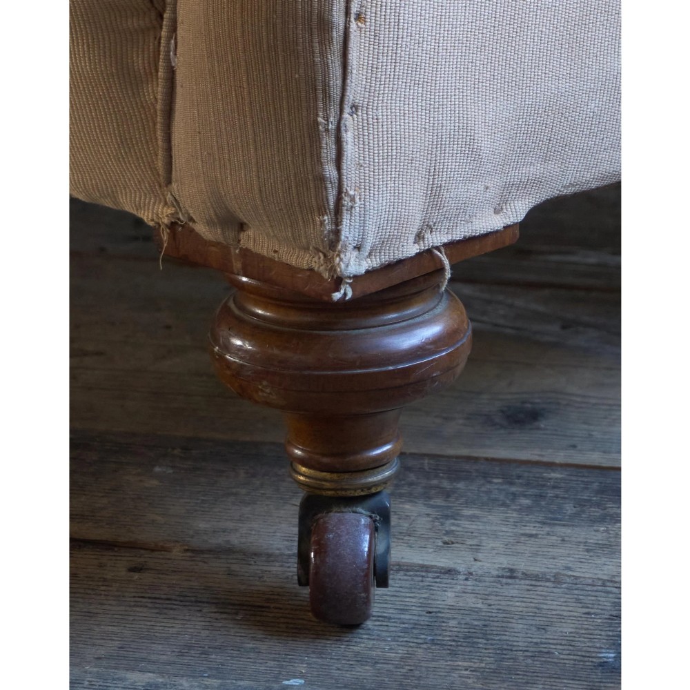 A 19th-century Chesterfield sofa upholstered in neutral beige calico fabric featuring rolled arms and turned wooden legs on brass castors. View XI