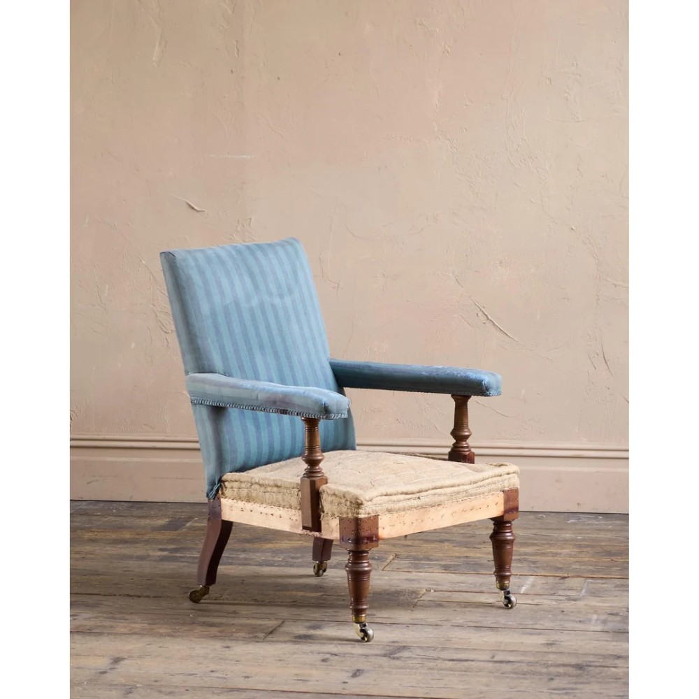 A Victorian mahogany open armchair with turned front legs, brass castors, open padded arms, and blue striped fabric upholstery.