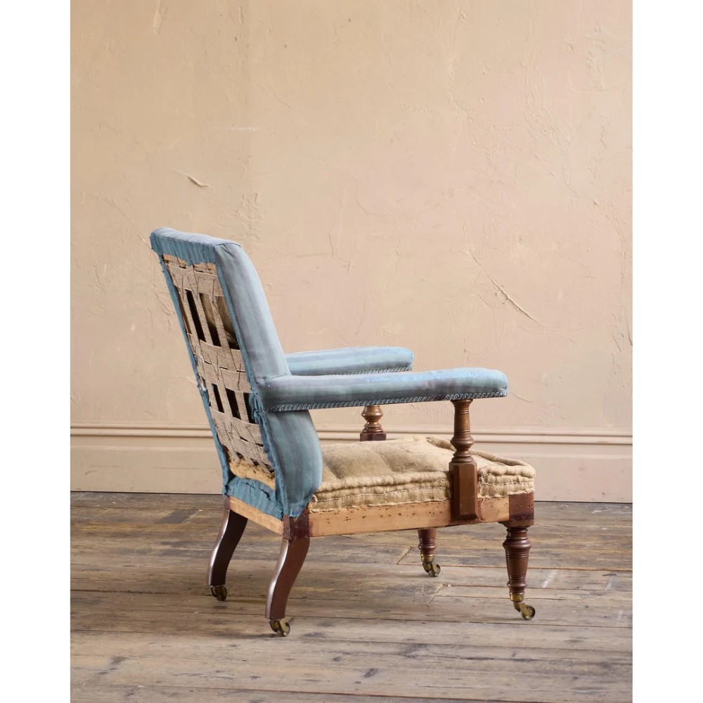 A Victorian mahogany open armchair with turned front legs, brass castors, open padded arms, and blue striped fabric upholstery. View VI
