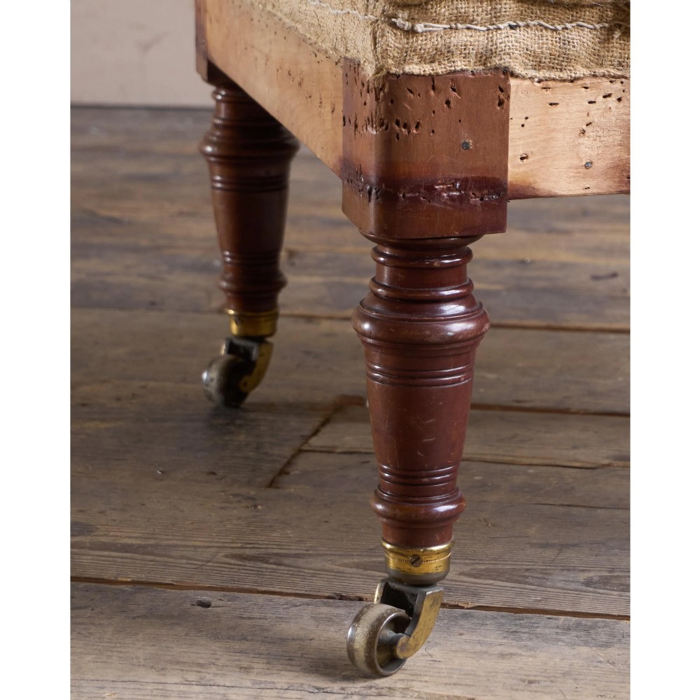 A Victorian mahogany open armchair with turned front legs, brass castors, open padded arms, and blue striped fabric upholstery. View VII