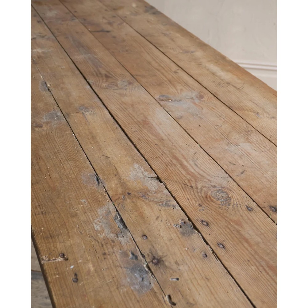 A long, narrow rustic wooden dining table featuring a thick plank top supported by X-frame trestle legs and a longitudinal stretcher. View IX