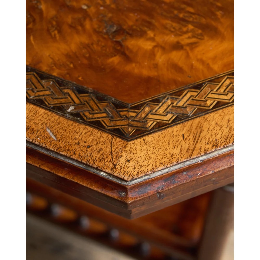 An octagonal Victorian side table featuring an amboyna wood veneer top with gilt borders, turned legs, a lower shelf with a spindle gallery, and brass castors. View IX