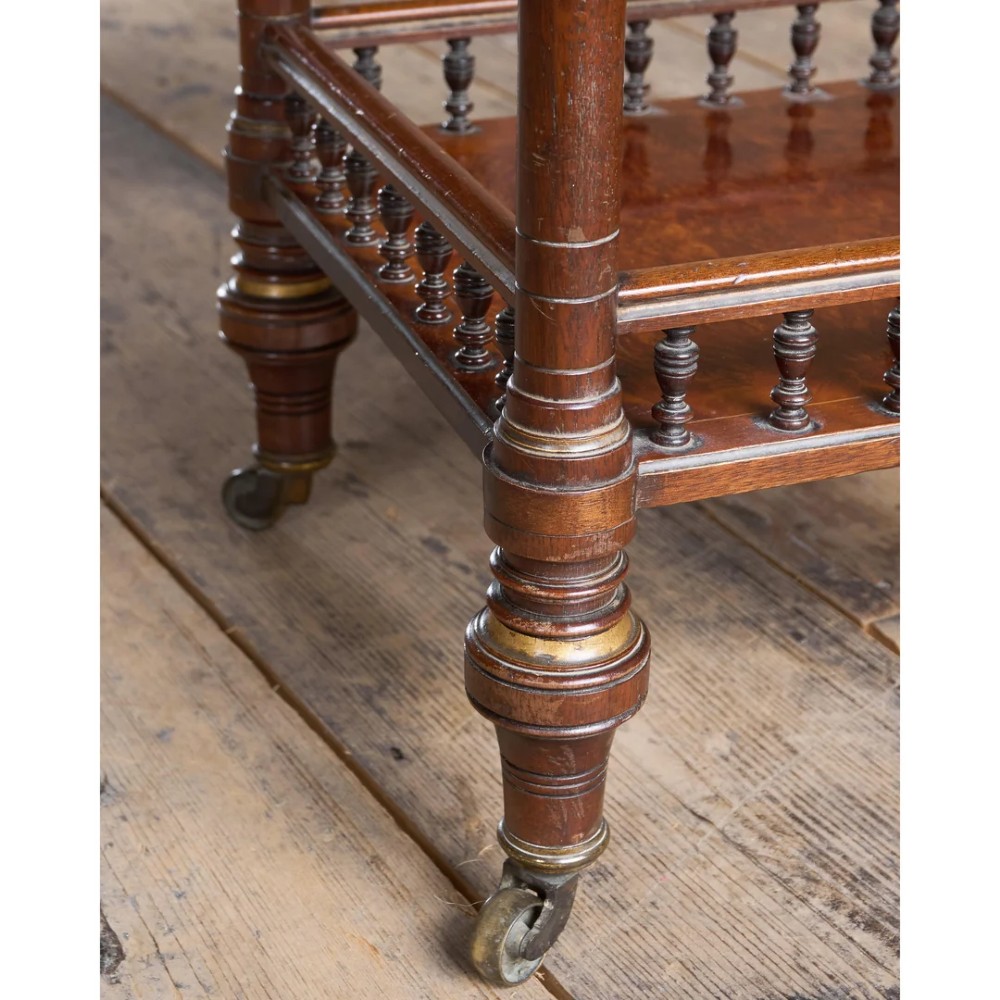 An octagonal Victorian side table featuring an amboyna wood veneer top with gilt borders, turned legs, a lower shelf with a spindle gallery, and brass castors. View XV