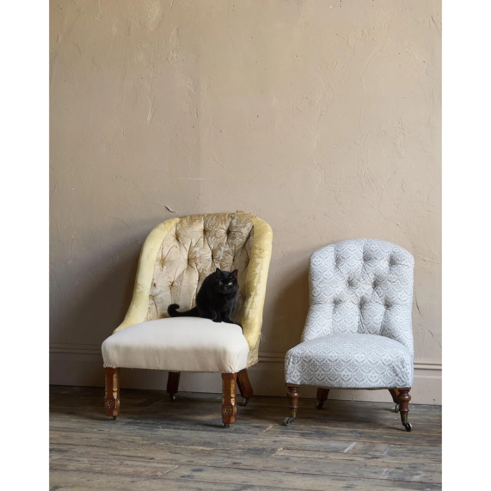 A low Victorian upholstered armchair featuring a deep button-backed yellow damask backrest, a plain off-white seat, and carved mahogany front legs on brass castors. View II