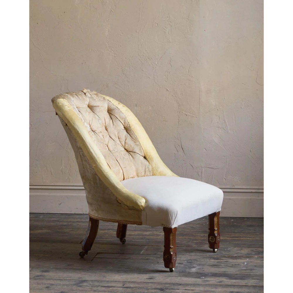 A low Victorian upholstered armchair featuring a deep button-backed yellow damask backrest, a plain off-white seat, and carved mahogany front legs on brass castors. View III