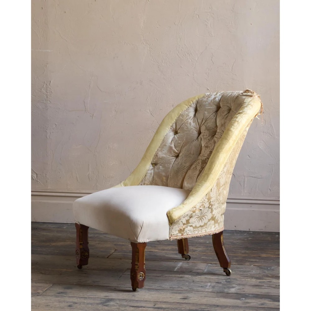 A low Victorian upholstered armchair featuring a deep button-backed yellow damask backrest, a plain off-white seat, and carved mahogany front legs on brass castors. View IV