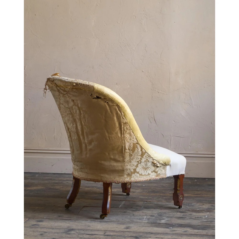 A low Victorian upholstered armchair featuring a deep button-backed yellow damask backrest, a plain off-white seat, and carved mahogany front legs on brass castors. View VIII