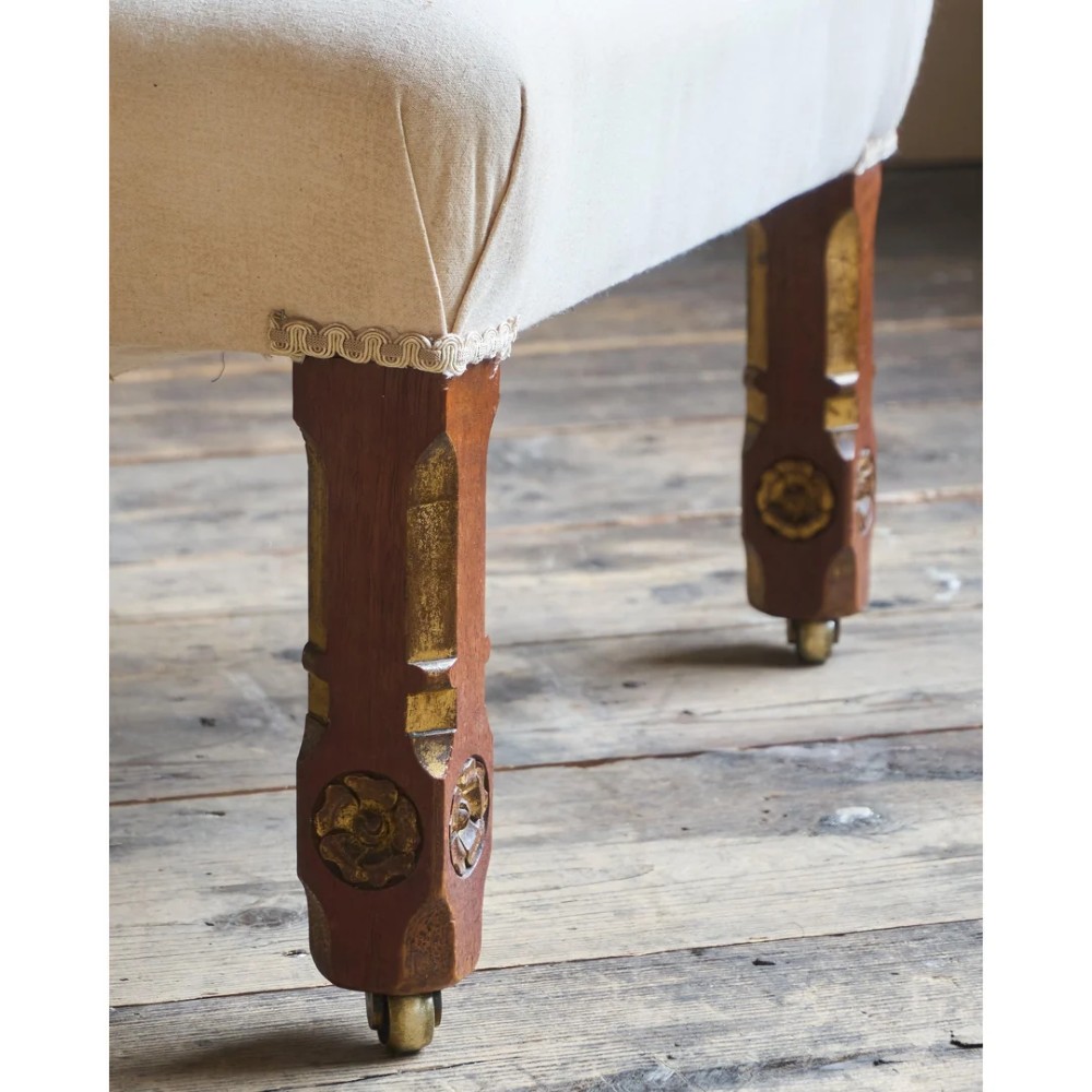A low Victorian upholstered armchair featuring a deep button-backed yellow damask backrest, a plain off-white seat, and carved mahogany front legs on brass castors. View X