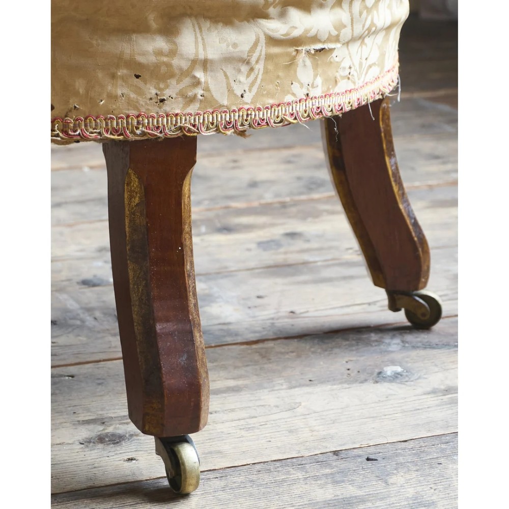 A low Victorian upholstered armchair featuring a deep button-backed yellow damask backrest, a plain off-white seat, and carved mahogany front legs on brass castors. View XI
