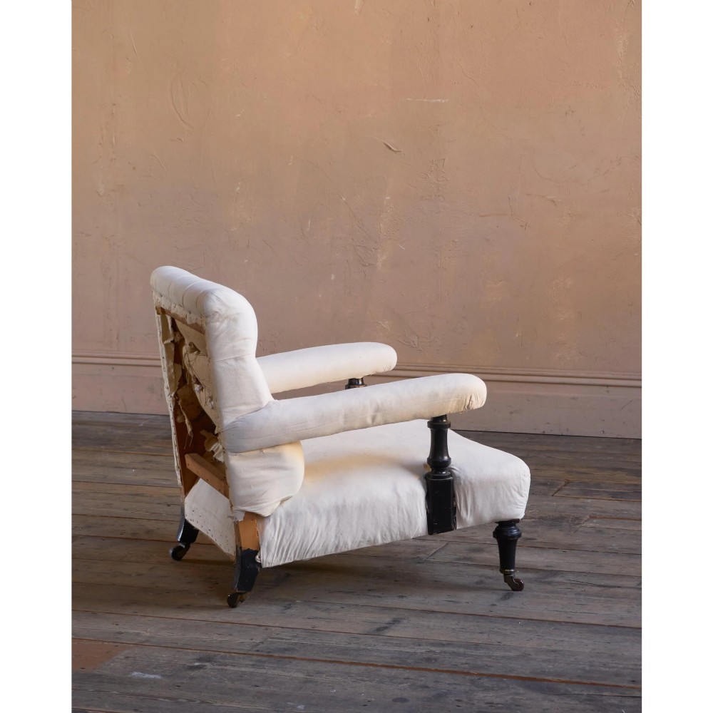 An antique Victorian open armchair upholstered in off-white calico fabric featuring a deep-buttoned backrest, padded arms, turned dark timber supports, and legs on castors. View III