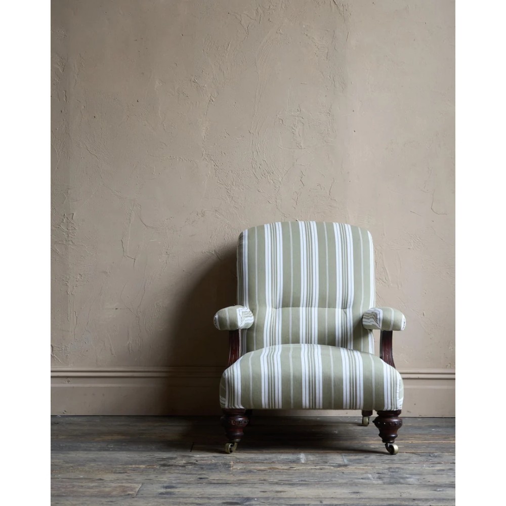 An oversized 19th-century open armchair upholstered in sage green and white striped fabric with carved mahogany arm supports and turned legs on brass castors. View II