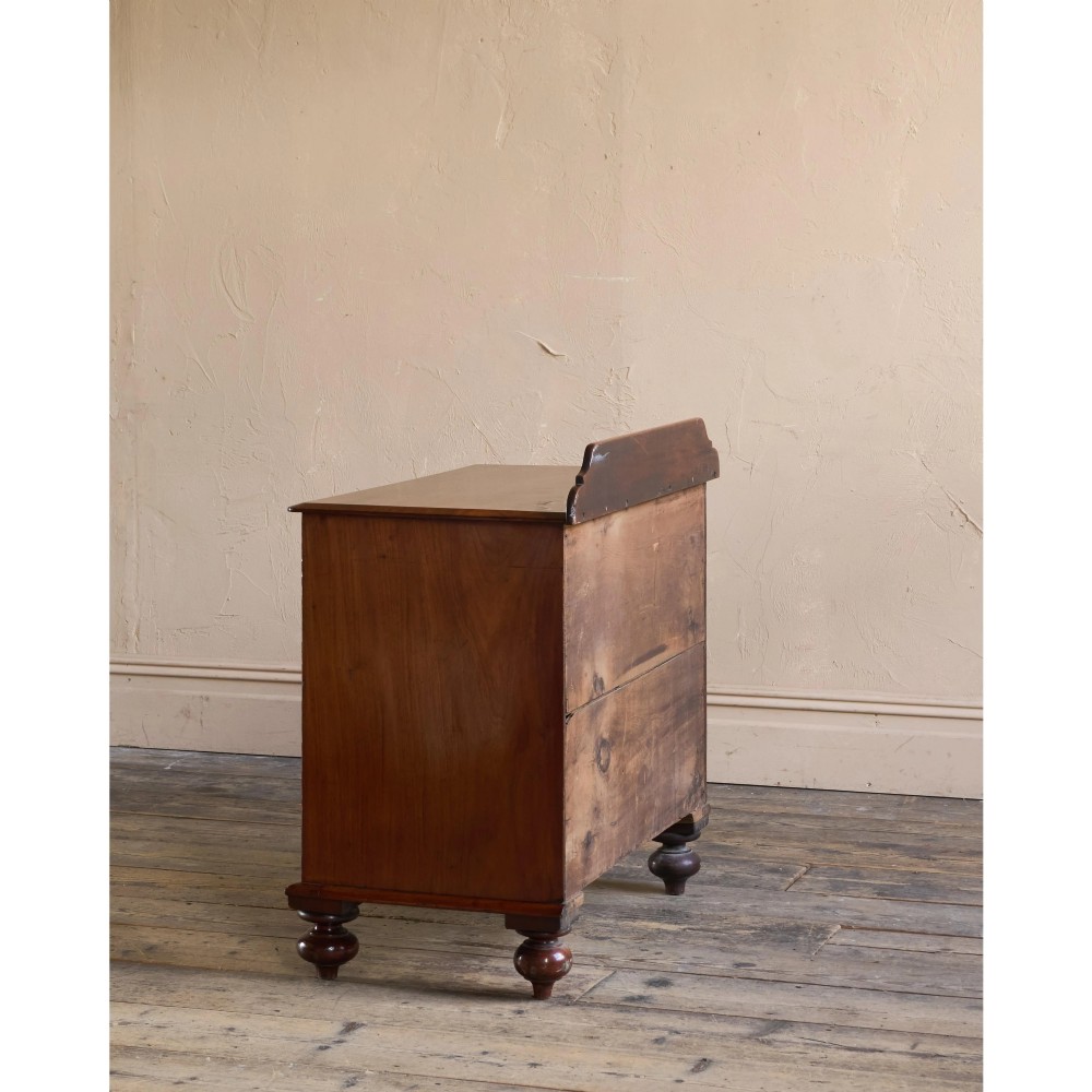 A nineteenth-century warm brown mahogany chest of drawers featuring flame mahogany veneer, turned handles, and a shaped gallery top. View III
