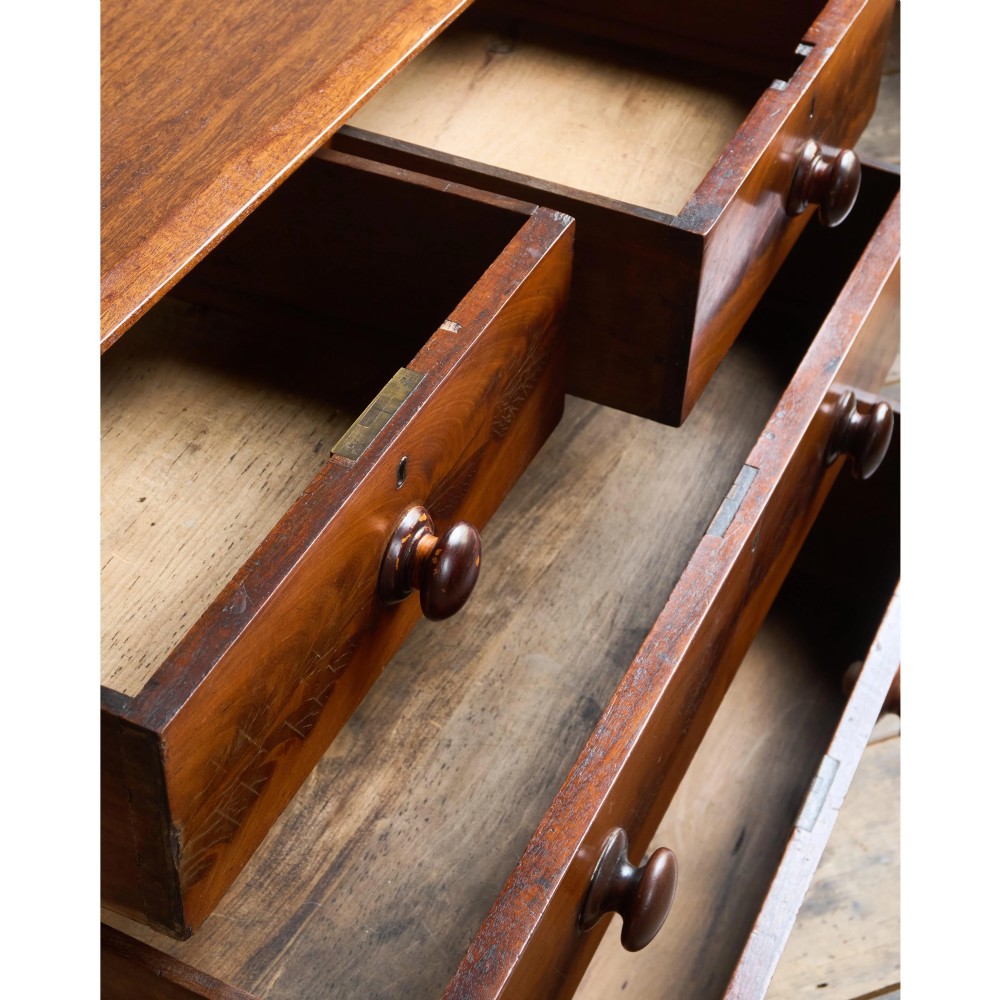 A nineteenth-century warm brown mahogany chest of drawers featuring flame mahogany veneer, turned handles, and a shaped gallery top. View VIII