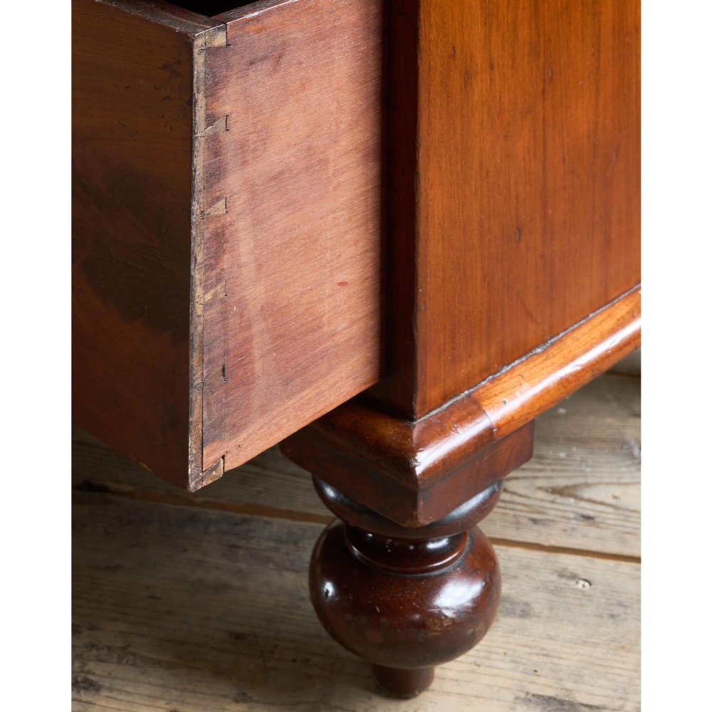 A nineteenth-century warm brown mahogany chest of drawers featuring flame mahogany veneer, turned handles, and a shaped gallery top. View XI