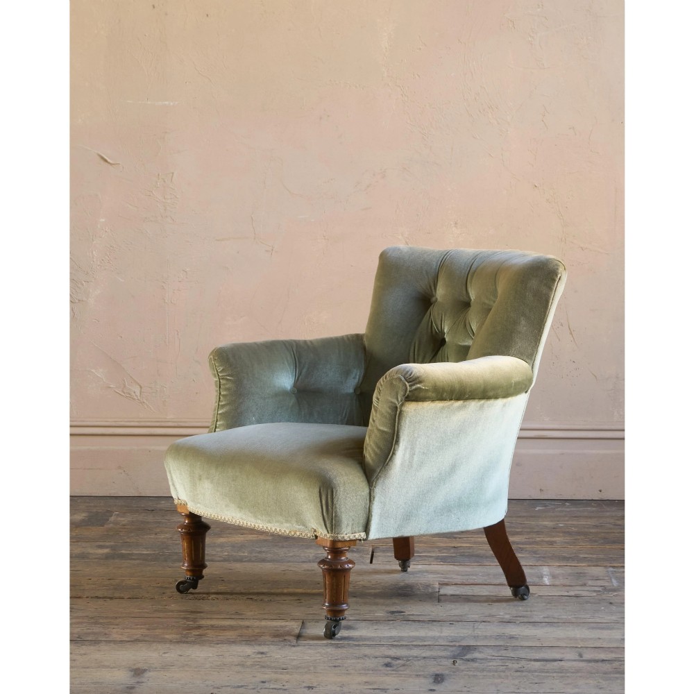 A 19th-century Victorian low armchair upholstered in light sage green velvet with a button-back design and turned wooden front legs on brass castors. View VII