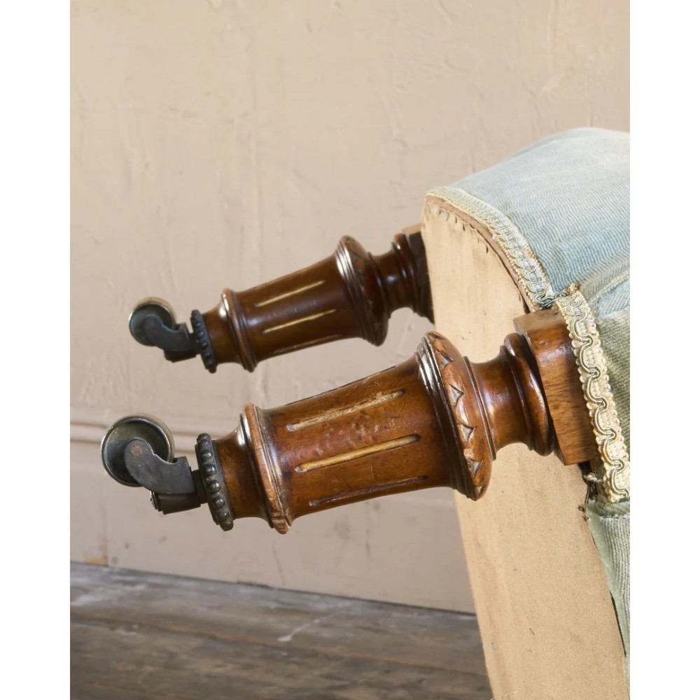 A 19th-century Victorian low armchair upholstered in light sage green velvet with a button-back design and turned wooden front legs on brass castors. View XI