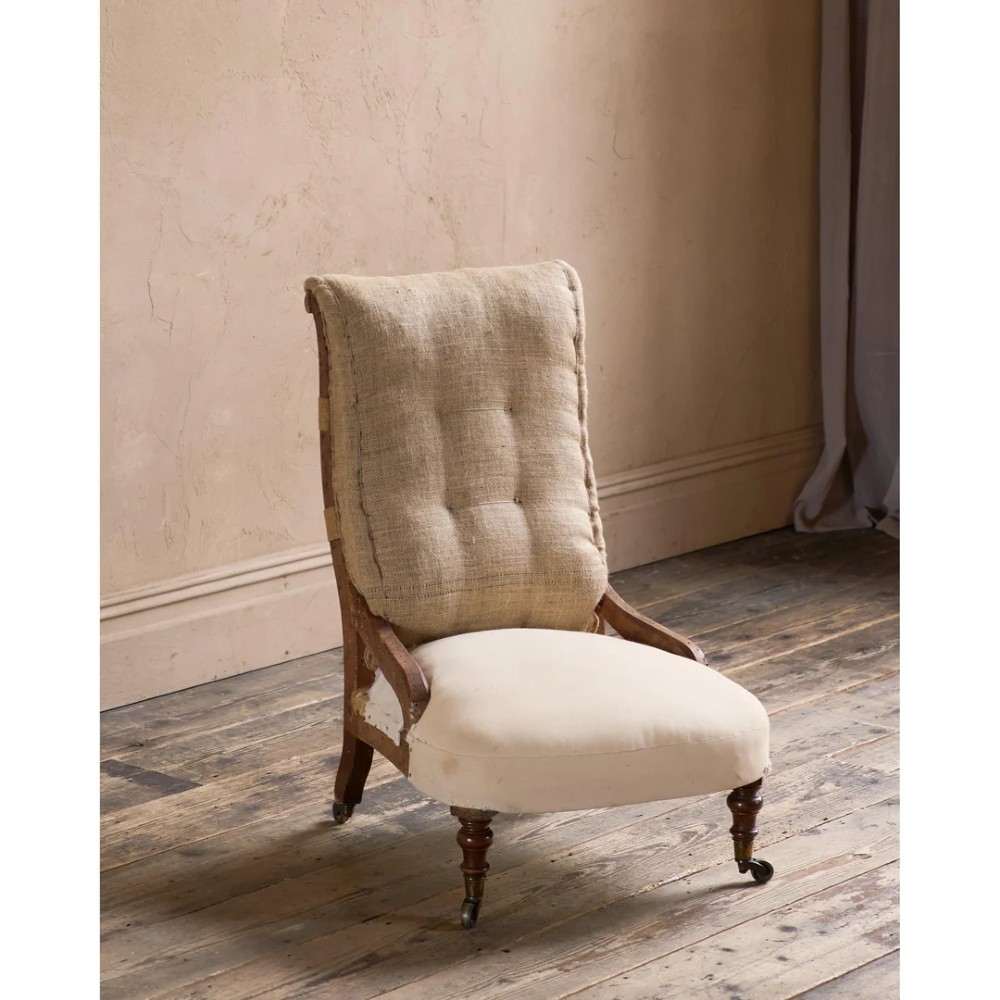 An early Victorian armchair featuring turned front legs on brass castors and hessian upholstery over a tufted backrest. View VII