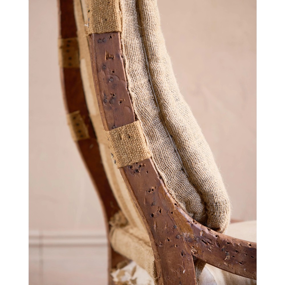 An early Victorian armchair featuring turned front legs on brass castors and hessian upholstery over a tufted backrest. View XI
