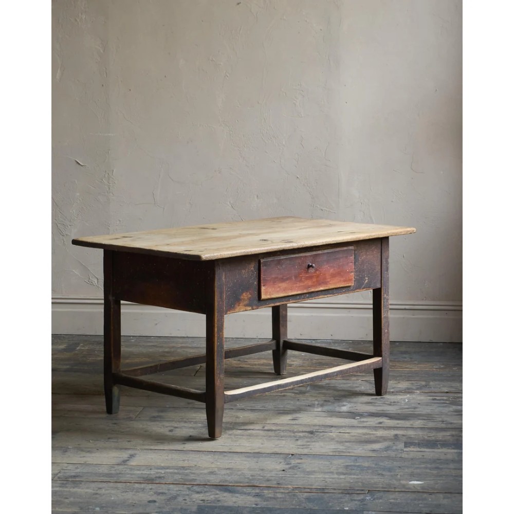 A rustic Swedish painted pine table featuring a scrubbed rectangular top, single frieze drawer, and dark painted base with box stretchers.