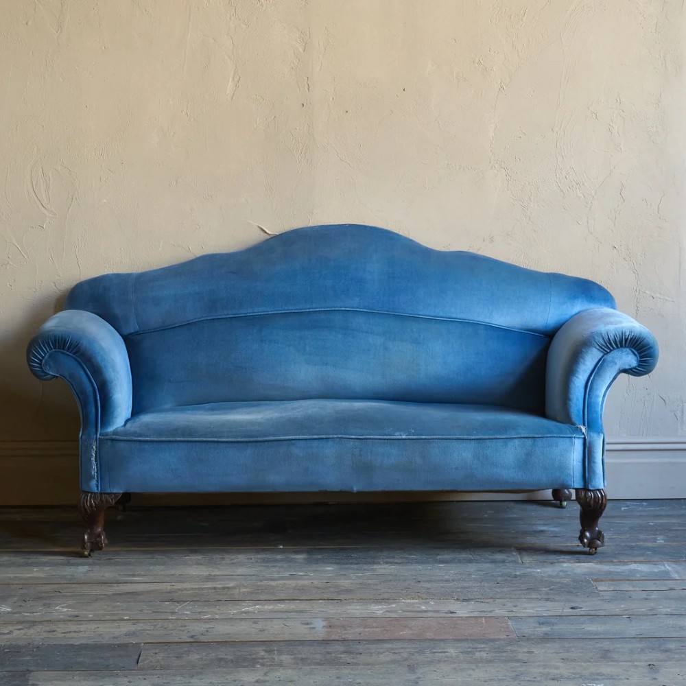 An antique blue velvet upholstered sofa featuring a curved back, rolled arms, and carved dark wooden cabriole legs with ball and claw feet on castors. View II