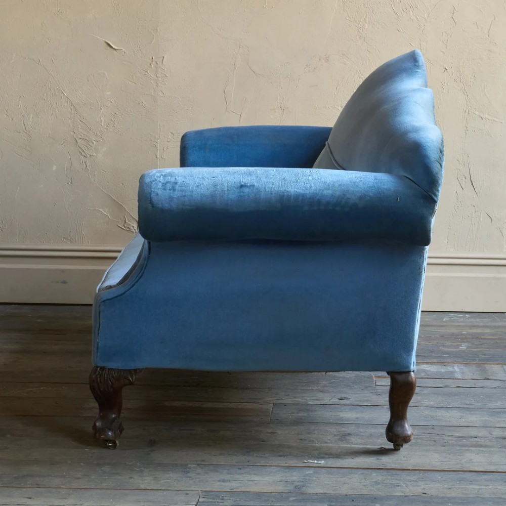 An antique blue velvet upholstered sofa featuring a curved back, rolled arms, and carved dark wooden cabriole legs with ball and claw feet on castors. View IV